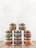 Multiple jars of Fat Toad Farm Caramel product on a wooden surface with a white background