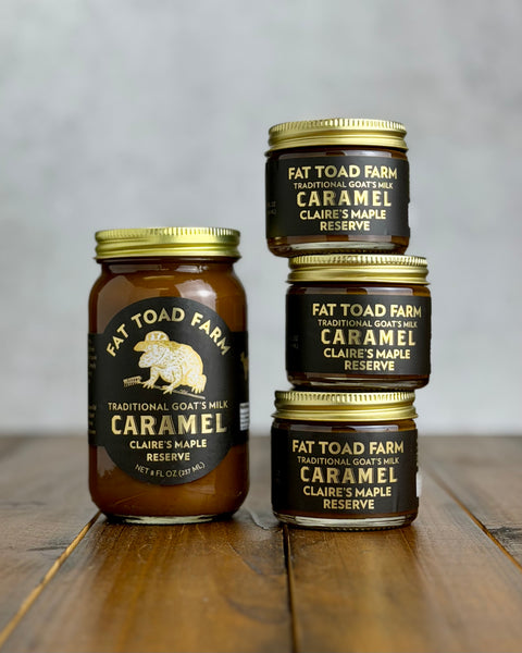 Three jars of Fat Toad Farm Caramel Claire's Maple Reserve on a wooden surface with a gray background.