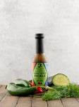 Bottle of Ghost Verde Pickle hot sauce with vegetables on a wooden surface