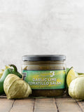 Jar of Garlic Lime Tomatillo Salsa from Butterfly Bakery of Vermont with tomatillos on a wooden surface